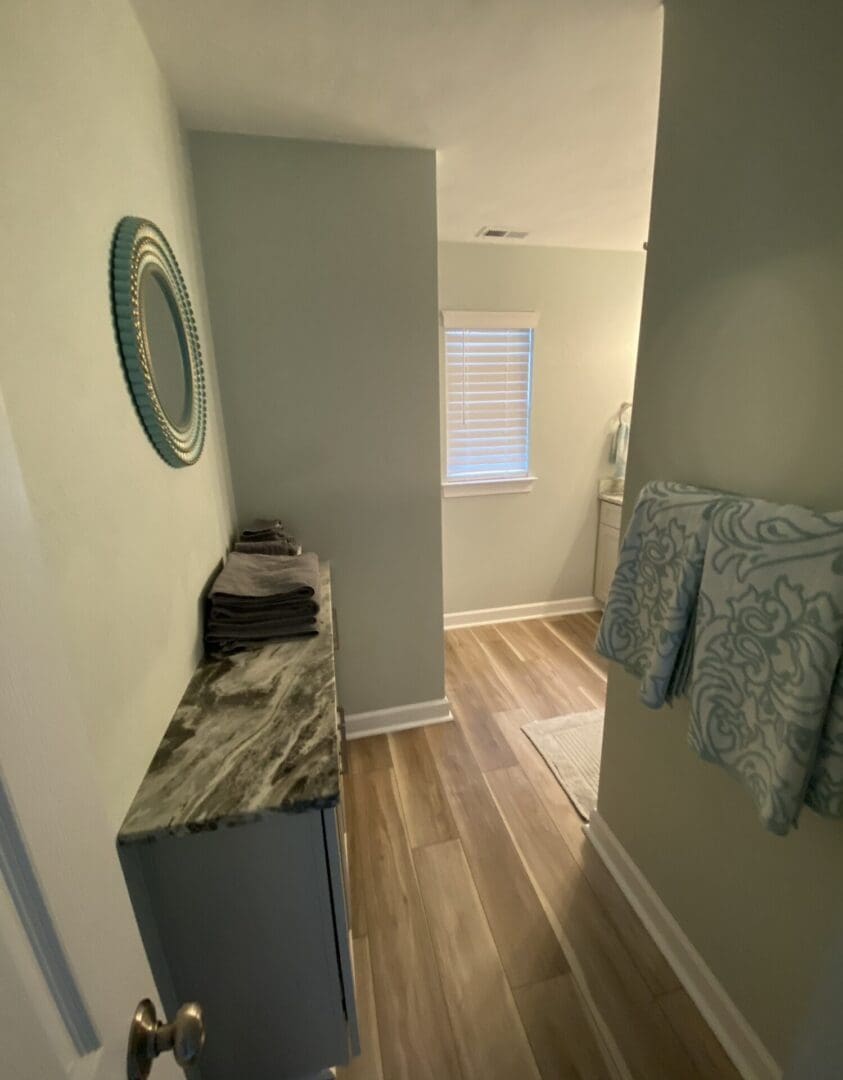 Narrow bathroom hallway with towels and mirror
